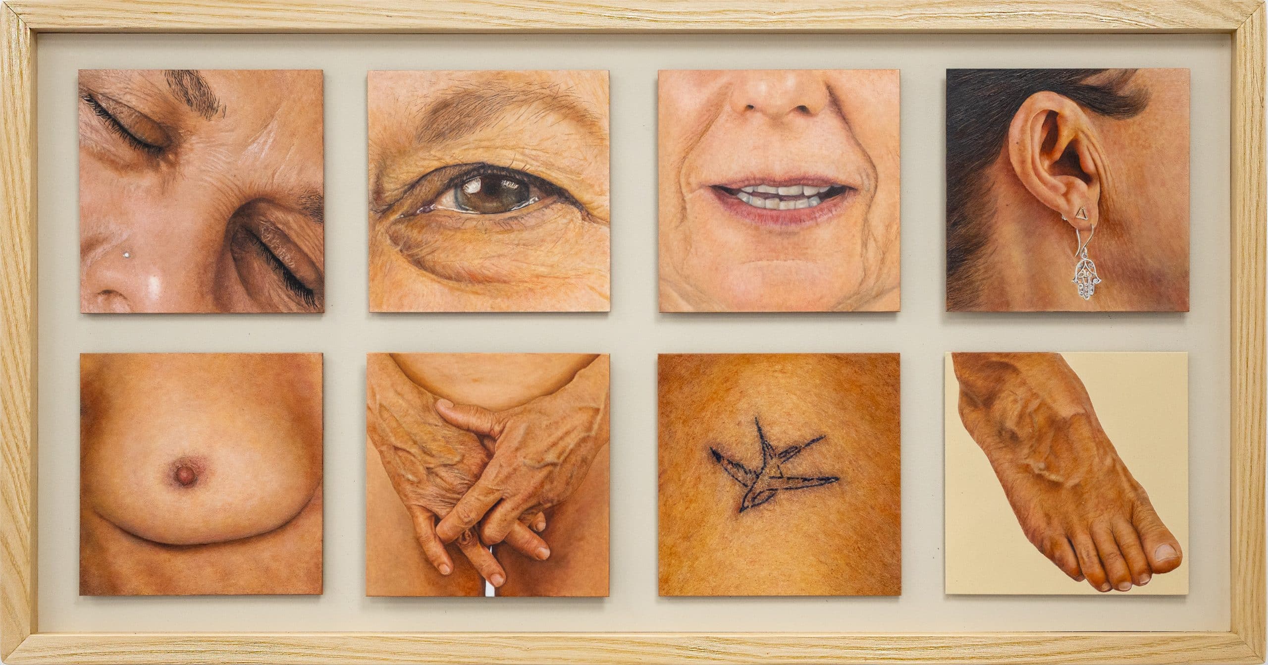 Photorealistic painting of eight intimate fragments of a mature woman’s body, including her eye, mouth, ear, hands, breast, tattoo, foot, and torso, arranged in a grid within a pale wooden frame.